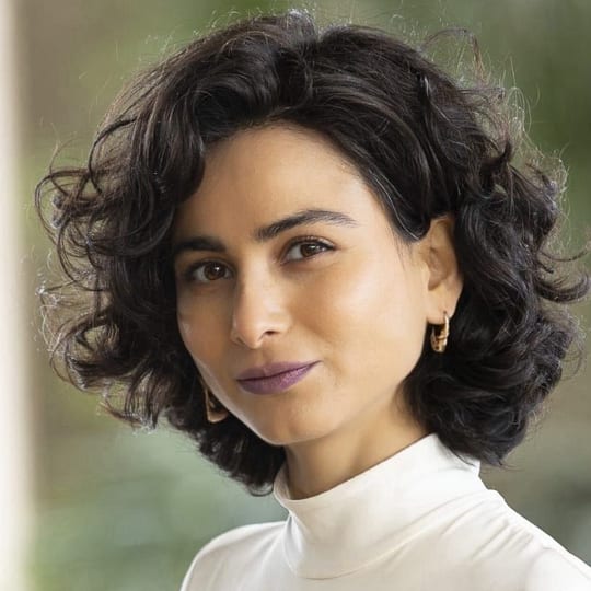 Paria Khamse, smiling, with dark curly hair and an ivory turtleneck.
